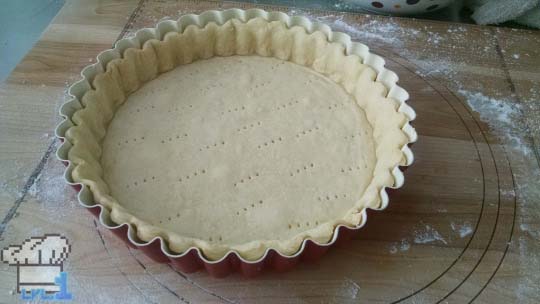 Tart dough has been rolled out and pressed into the pan for the tart shell before baking.