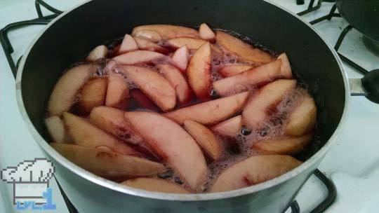 Sliced peaches being poached in liquid before assembling them into tart shell to be baked.