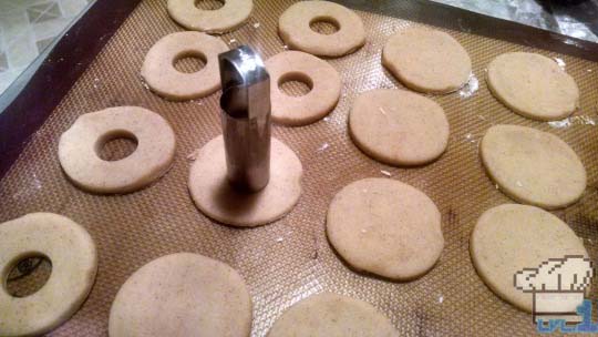 Circular cookies being punched out with round cookie cutters before baking.