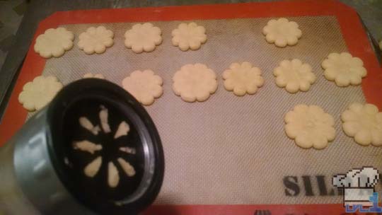 Flower cookies from cookie gun on pan ready to be baked.