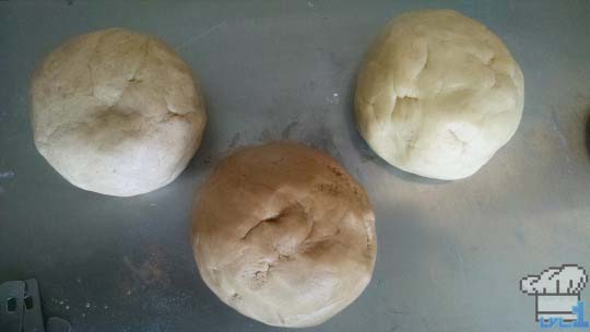 Cookie dough separated into three balls for rolling out.