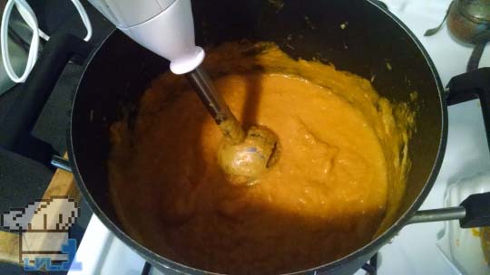A pot of Good Soup being pureed by an immersion blender to a smooth consistency.