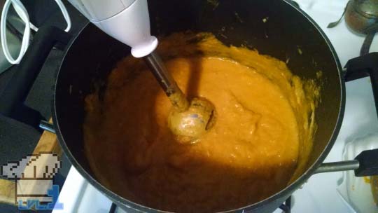 A pot of Good Soup being pureed by an immersion blender to a smooth consistency.