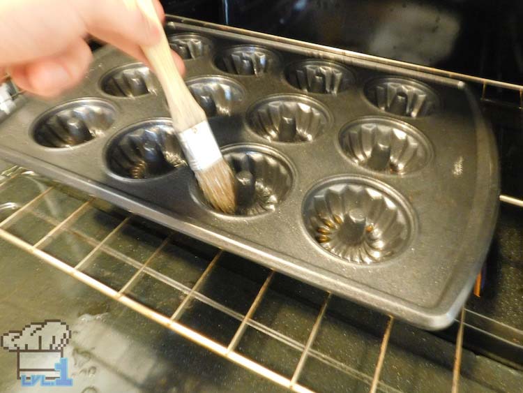 Brushing the mini bundt baking pan with butter before adding the batter to it. 