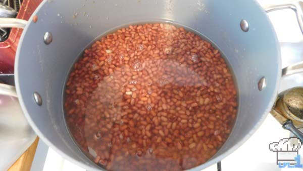 Dried red adzuki beans soaking in a pot of water to rehydrate.
