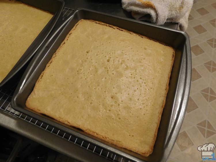 A pan of freshly baked almond genoise cake removed from the oven and cooling before slicing.