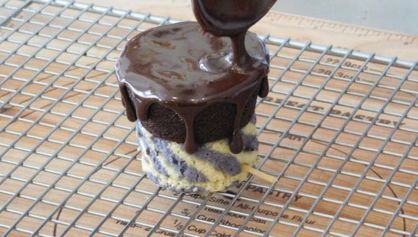Spooning the warm chocolate fudge over the top of the chocolate cupcake to create slow drips down the side of the Legend of Zelda Spirit Tracks cannon car.