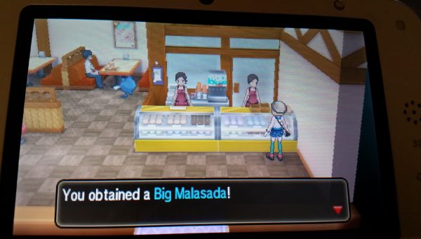 Screenshot from the Pokemon game series of a big malasada being purchased at the bakery.