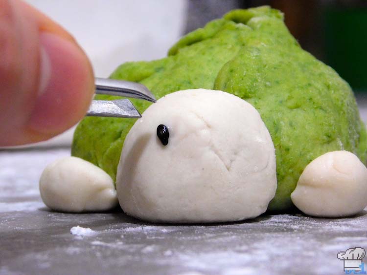 Applying the black sesame seed eyes to the Paper Mario Koopa Bun with tweezers, before steaming.