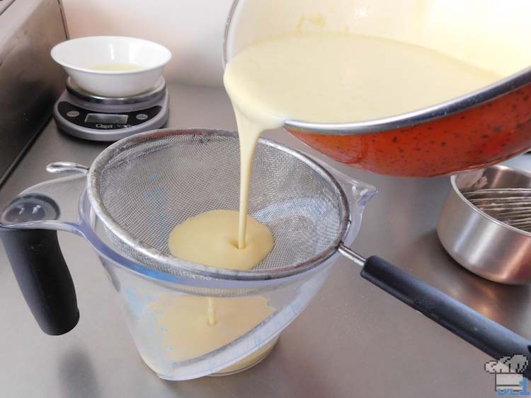 Filtering the crepe batter through a mesh strainer to get out all of the clumps and to make a smooth textured batter.